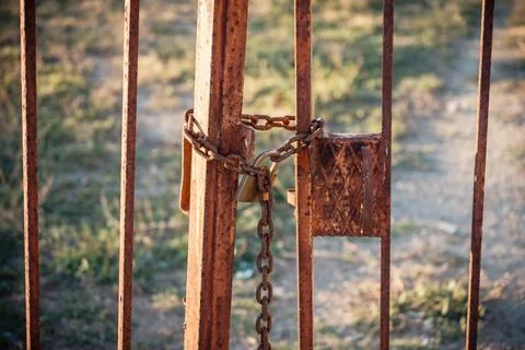 Old rusty metal gate secured with heavy iron chain and padlock outdoors Stock Photos