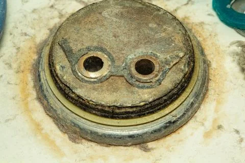 Old rusty metal part with two holes on a light surface detail Фото