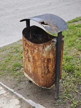 Old rusty metal trash bin with a damaged lid Stockfoto's