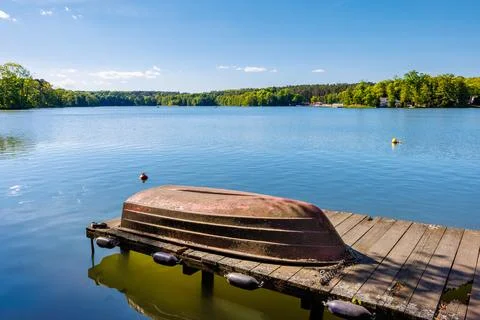 Old rusty overturned boat chained to a small wooden pier. Beautiful summer .. Stock Photos