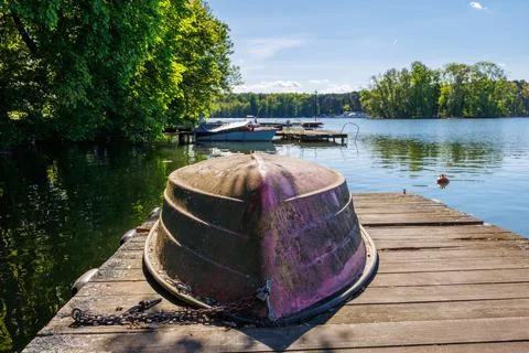 Old rusty overturned boat chained to a small wooden pier close-up. Beautifu.. Stock Photos