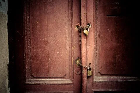 Old rusty padlock and chain on the wooden gate home Stock Photos