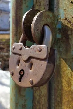 An old, rusty padlock with a chain hanging from the gate Stock Photos