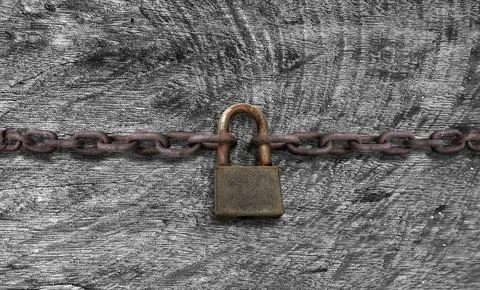 An old rusty padlock closed on a massive chain on vintage wooden table Foto stock