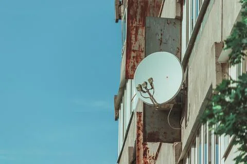 Old rusty panel house with a white satellite dish for television. Stock Photos