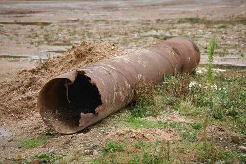 Old rusty pipe lying on the green grass Stock Photos
