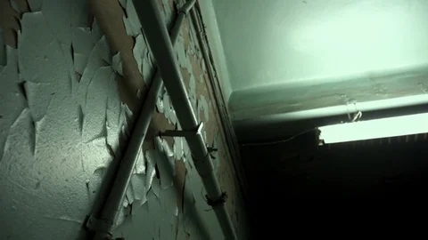Old rusty pipes and a long fluorescent lamp hanging on a concrete ceiling. Stock Footage 108001710