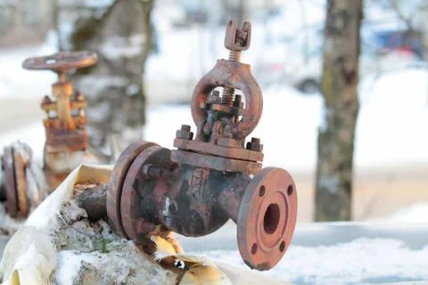 Old rusty shut-off valve on a heating pipe on a winter background Stock Photos