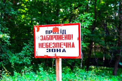 Old rusty signs of caution on the tree. Dead military unit. Consequences of t Stock Photos