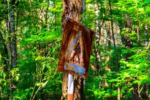 Old rusty signs of caution on the tree. Dead military unit. Consequences of t Foto stock