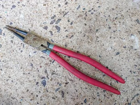 Old rusty snap ring pliers with red handles isolated on concrete texture Stock Photos