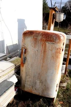 Old rusty soviet refrigerator Mir and metal washbasin in the background in .. Stock Photos