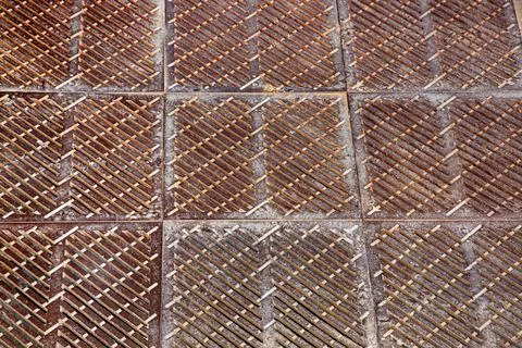 Old rusty square shaped drainage grate, the surface of the storm system. Stock Photos