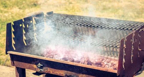 An old rusty steaming barbecue when lighting in garden Stock Photos