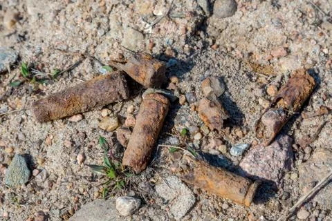 Old rusty submachine gun shells in the sand on the territory of the former sh Stock Photos
