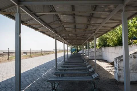 Old rusty sun canopy with sun loungers and lanterns on the sea promenade Stock Photos