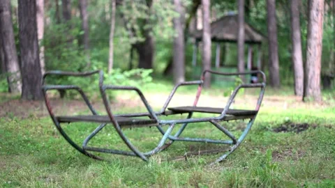 Old rusty swing gently sways in a peaceful forest clearing. Stock Footage 338415337
