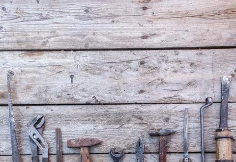 Old, rusty tools lying on a black wooden table. Hammer, chisel, hacksaw, meta Foto stock