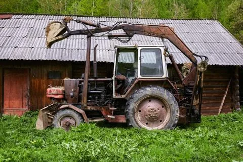 Old rusty tractor with dragging bucket Photos