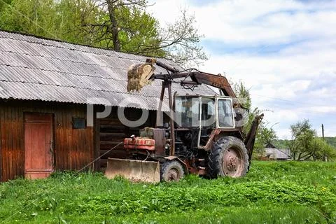 Old rusty tractor with dragging bucket Stock Photos
