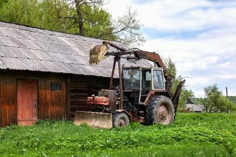 Old rusty tractor with dragging bucket Stock Photos