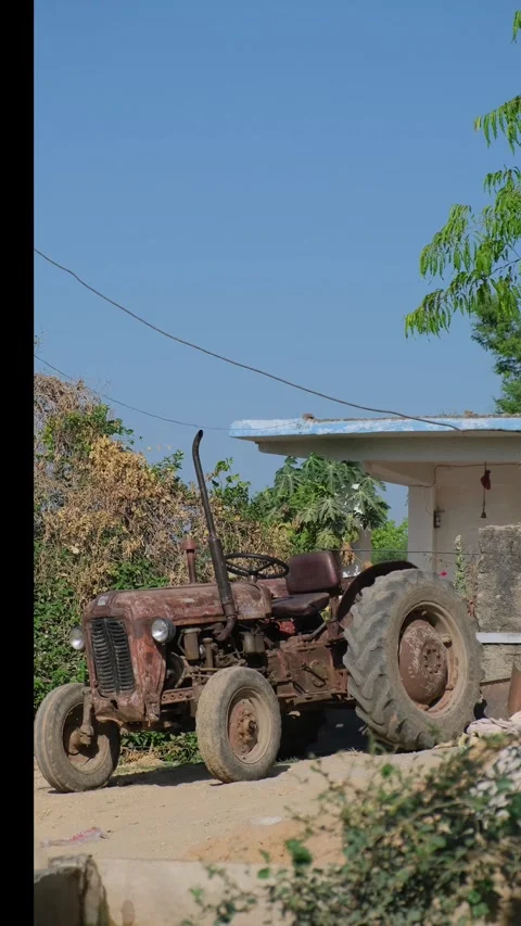Old rusty tractor parked in a rural Indian village courtyard on a sunny day Video stock 333451535