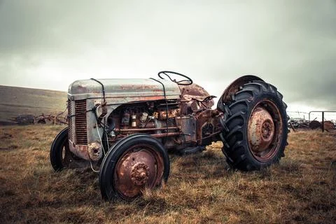 Old rusty tractor in poor condition on a pasture in Iceland. Stock Photos