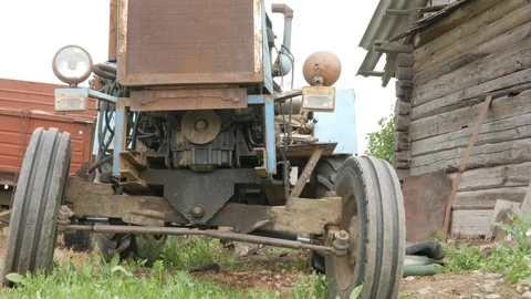 An old rusty tractor stands near the field. The machine for agriculture is Stock Footage 76974938