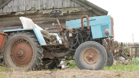 An old rusty tractor stands near the field. The machine for agriculture is Stock Footage