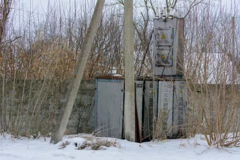 An old rusty transformer in winter in an abandoned and destroyed factory agai Stock Photos