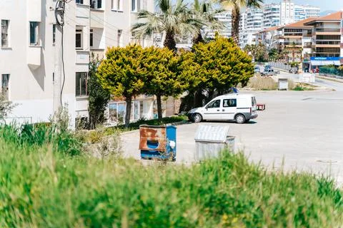 Old rusty trash dumpster standing near residential building in a south city. The Stock Photos