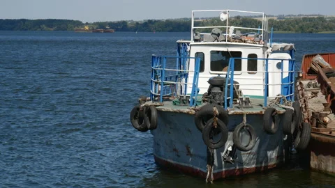 An old rusty tugboat is moored to the platform of a floating crane near Stock Footage 141499113