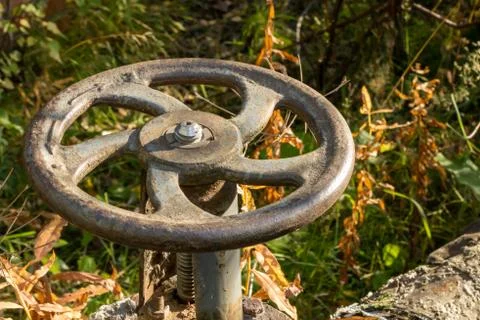 Old rusty valve close up on greenery background. Stock Photos