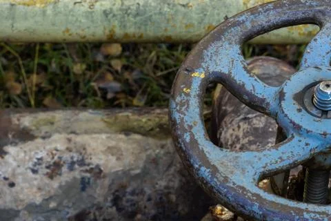 Old rusty valve close up on greenery background. Stock Photos