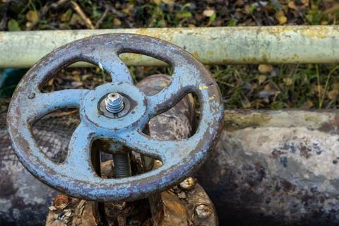 Old rusty valve close up on greenery background. Stock Photos