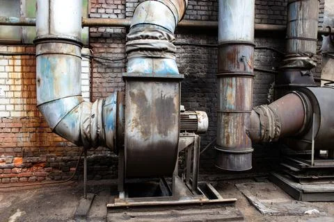 An old rusty ventilation unit in an abandoned metal processing plant. Dark sm Stock Photos