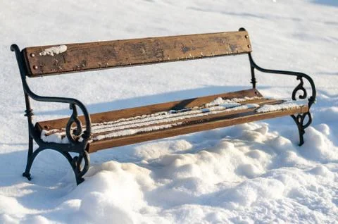 Old rusty vintage empty bench in snow covered park Stock Photos