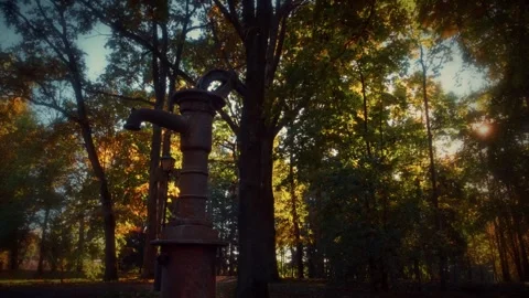 Old rusty water pump standing in front of blurred autumn foliage Stock Footage 292788658