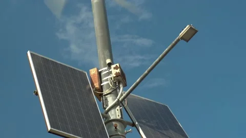 An old rusty wind turbine on a pole. A solar panel on a pole in the middle of a Stock Footage 209994791