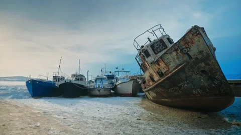 An old rusty wrecked ship, graffiti-painted, against a backdrop of beautiful new Stock Footage 257763944