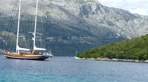 Old Sailboat Passes the Lighthouse and Mountains Stock Footage 54896653