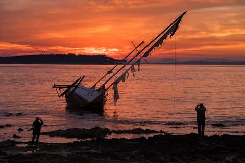 Old sailboat stranded in front of Gorriti Island, during sunset Stock Photos