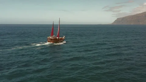 An old sailing ship with crimson sails cruises across the ocean in search of Video stock 147689472