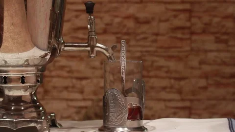 From an old samovar pour boiling water into an antique glass Stock Footage 84570896
