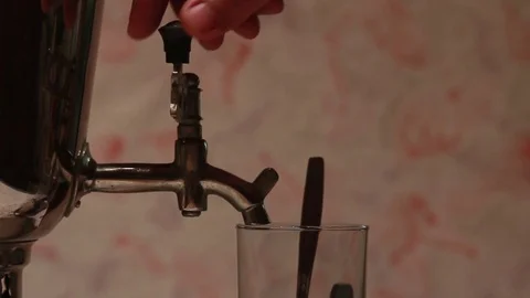 From an old samovar pouring boiling water in an old cup Stock Footage 84570655