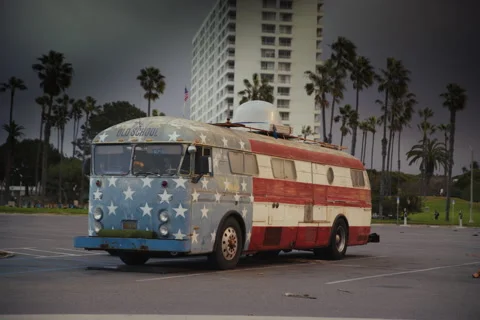 Old School American Flag Bus in Scenic Parking Lot with Palm Trees Stock Footage 297362753