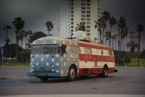 Old School American Flag Bus in Scenic Parking Lot with Palm Trees Stock Footage 297362787