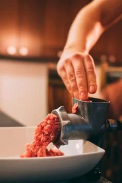 Old school meat blender grinder and man hands grinding red beef  into the plate Stock Photos