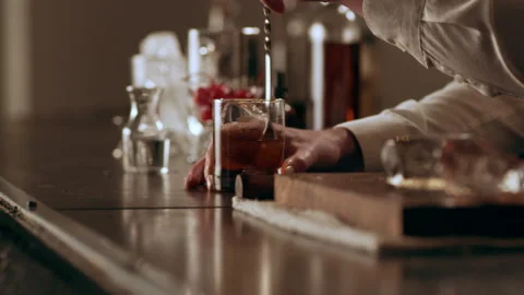 Old school mixologist stirring the liquid in a glass with a long spoon in interi Stock Footage 199456491