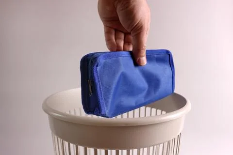 An old school pencil case is thrown into the trash can for recycling Stock Photos